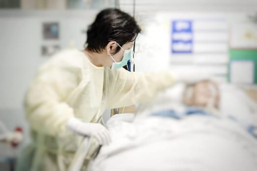 Asian women 40s years old in gown coat is a patient relative taking care of the CRE. or VRE. infected elder patient 80s years old on bed in the hospital.