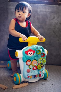 Cute boy with toy walker in playroom.
