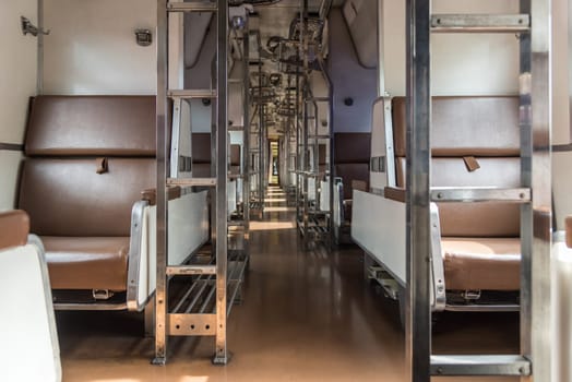 Inside of old public Thai railway train cabin with seats, handrails, fan and interior in vintage style service for passenger transport