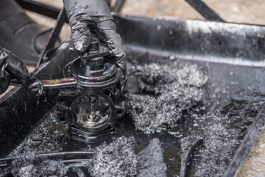 Car mechanic or serviceman disassembled car dirty engine for cleaning fuel injection and air flow system engine parts for fix and repair problem at car garage or repair shop
