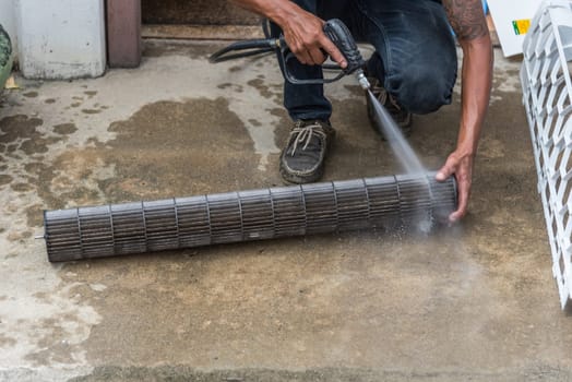 Worker to cleaning coil cooler of air conditioner by water for clean a dust on the wall in customer home when maintenance service