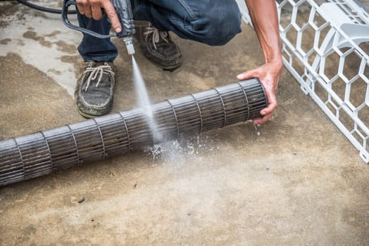 Worker to cleaning coil cooler of air conditioner by water for clean a dust on the wall in customer home when maintenance service