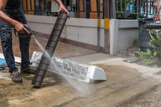 Worker to cleaning coil cooler of air conditioner by water for clean a dust on the wall in customer home when maintenance service