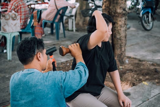 Thai woman to take of service Thai massage by wooden hammer for treat aches and pains. The service comes in the outdoor garden.