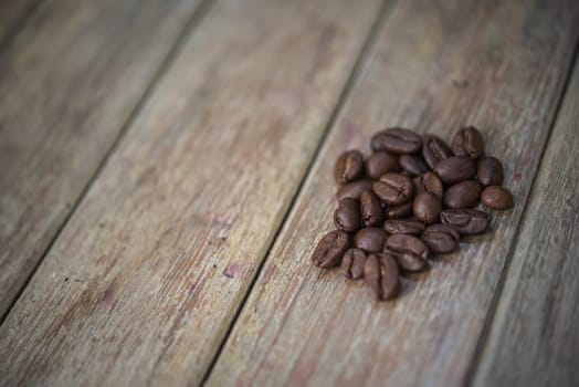 Coffee beans and roasted coffee beans on wooden table in a cafe or coffee shop, traditional vintage style concept