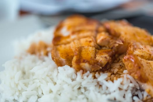 Barbecued red pork in sauce with rice and cucumber served in dish on wood table in Thai restaurant at Thai street food market at Bangkok Thailand