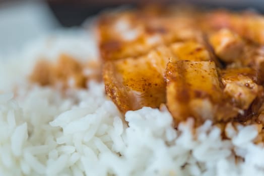 Barbecued red pork in sauce with rice and cucumber served in dish on wood table in Thai restaurant at Thai street food market at Bangkok Thailand