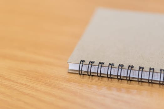 Notebook or note paper sheet in retro style with brown cover and blank white paper on wooden table or desk in business and education concept