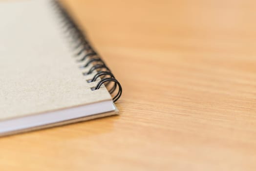 Notebook or note paper sheet in retro style with brown cover and blank white paper on wooden table or desk in business and education concept