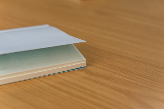 Notebook or note paper sheet in retro style with brown cover and blank white paper on wooden table or desk in business and education concept