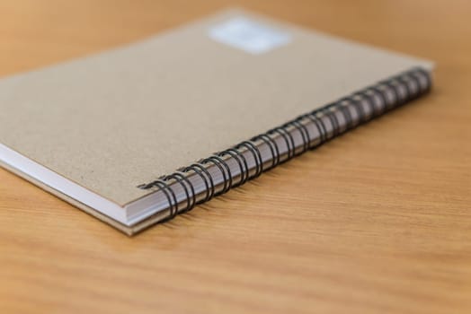 Notebook or note paper sheet in retro style with brown cover and blank white paper on wooden table or desk in business and education concept