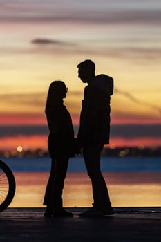Cute couple holding hands on the background of a sunset. Mid shot
