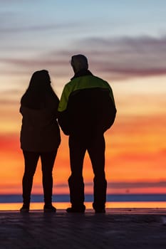 A couple of people standing on the background of bright sunset. Vertical shot