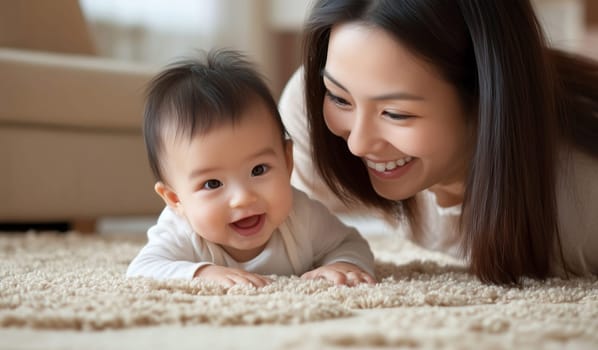 Happy Asian young mother playing with her cute baby together lying on the floor in living room at home