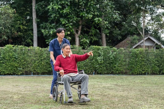 A compassionate healthcare worker joyfully pushes a senior man in a wheelchair, both appreciating the beautiful surroundings of a peaceful garden.