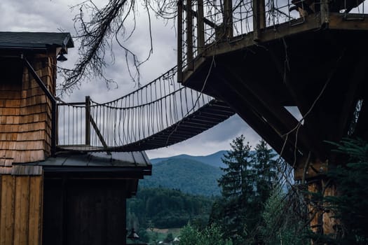 A cozy wooden treehouse, complete with a suspended bridge, blends into the natural surroundings. High quality photo