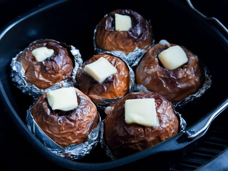 Baked apples with butter in foil. Delicious homemade dessert in baking tray.