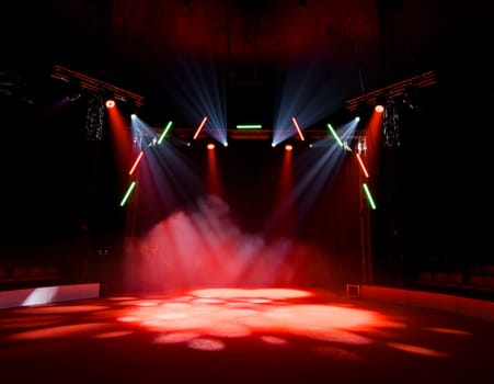 Colorful stage lights illuminating empty circus arena with smoke effects.
