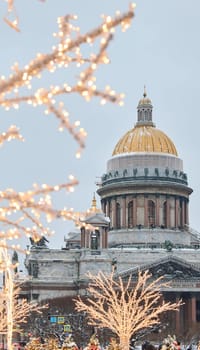 a snow-covered New Year's city decorated for the celebration of the new year, the golden dome of St. Isaac's Cathedral, walking tourists. High quality photo