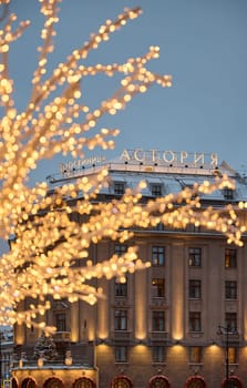 Russia, St.Petersburg, 30 December 2023: the famous Astoria hotel, a snow-covered New Year's city decorated for the celebration of the new year, walking tourists. High quality photo