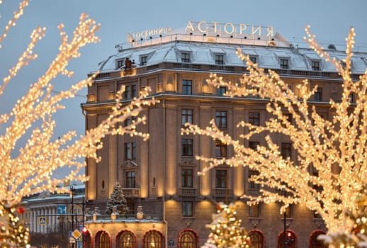 Russia, St.Petersburg, 30 December 2023: the famous Astoria hotel, a snow-covered New Year's city decorated for the celebration of the new year, walking tourists. High quality photo