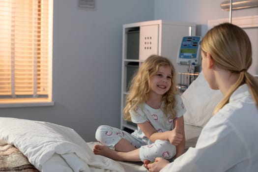 A young girl shares a joyful moment with a caregiver in a hospital, showcasing compassion and warmth