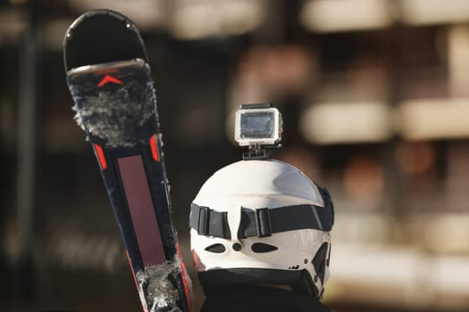 Blogger skier with skis, protective helmet and video camera on a helmet in the mountains