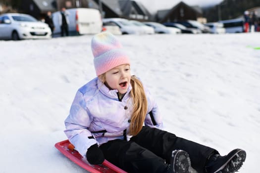 A girl with red bob sledding in the snow in the mountains