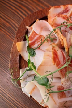 Beautiful slicing of fat and delicious fresh bacon on a wooden plate of unusual shape in the restaurant