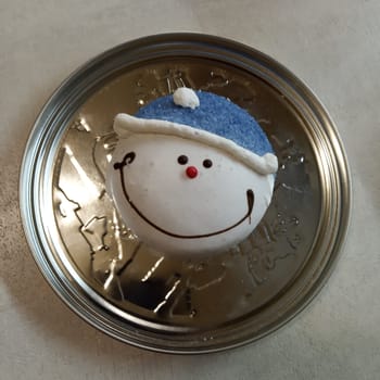 a smiling snowman gingerbread cookie resting on a metallic surface, creating a delightful contrast between the warmth of the festive treat and the coolness of the metal. Festive Delight