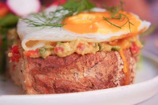 A savory bread dish featuring a fried egg, herbs, and vegetables.