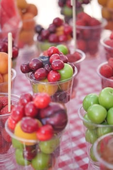 Fruit cups filled with various fresh fruits at an outdoor market.