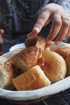 A hand reaches for warm bread rolls in a cozy setting.