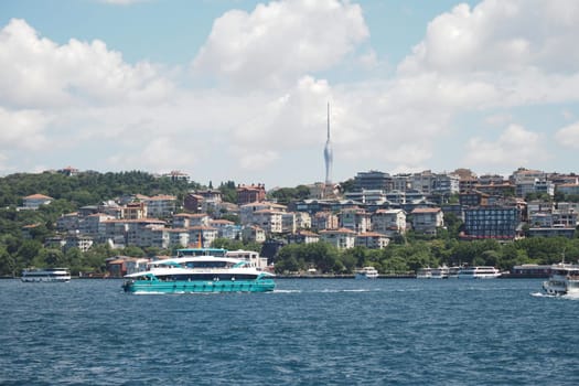 A ferry glides by Istanbul's green shoreline under clear skies.