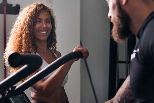 cheerful sportswoman smiling happy speaking with confident muscular bodybuilder at gym, concept of fitness and active lifestyle