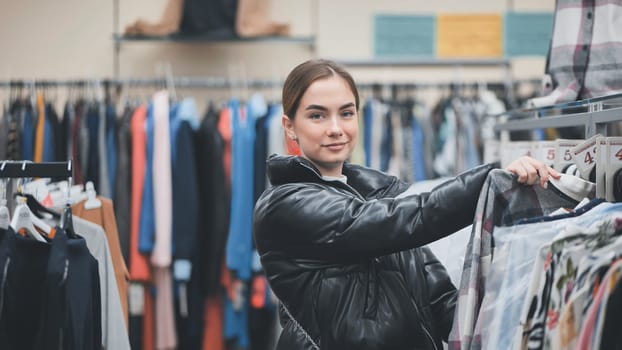 Stylish shopper examining clothing rack, exploring latest fashion trends in upscale retail environment