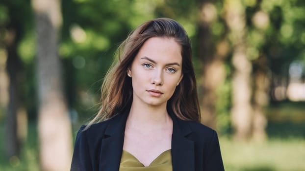 Confident businesswoman standing in lush park setting, professional blazer and blouse highlighting corporate confidence and urban outdoor style