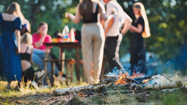 Teenage friends gathering around campfire, laughing and sharing stories during woodland evening hangout