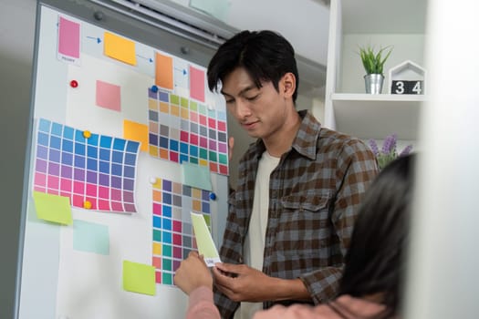 A diverse graphic design team member presenting color options while engaging in project discussions in a contemporary workspace.