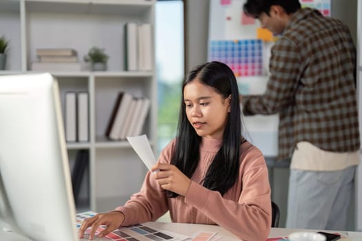 A diverse graphic design team member focused on evaluating color palettes while collaborating in a contemporary creative workspace.