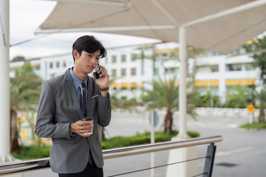 A suited man engages in a phone call while enjoying coffee, showcasing work-life balance.