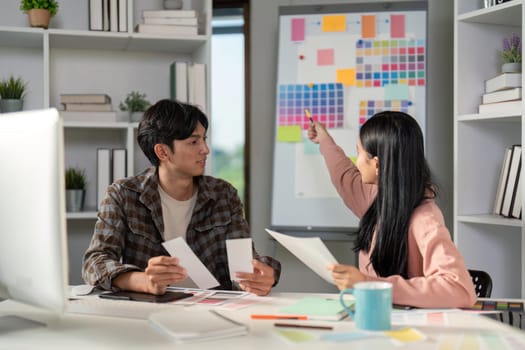 A diverse graphic design team discussing color selections and project concepts while collaborating in a bright and modern workspace.