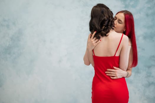 A close-up portrait of two tenderly embracing women dressed in identical red dresses. Lesbian intimacy