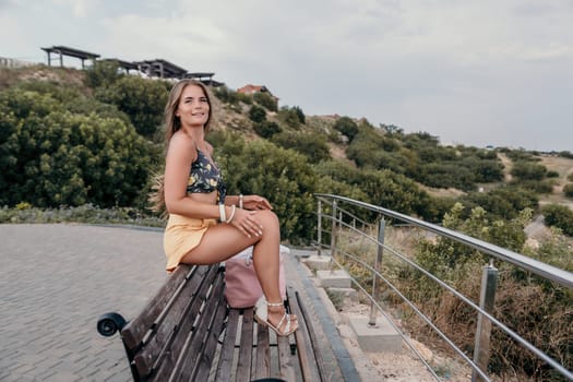 Woman travel sea. Happy tourist taking picture outdoors for memories. Woman traveler looks at the edge of the cliff on the sea bay of mountains, sharing travel adventure journey.