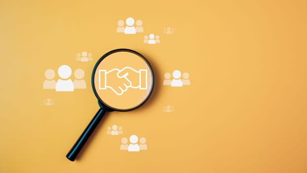 Team management concept, Human resources, recruitment concept, HRM administration or human resource management concept. The handshake icon in a magnifying glass placed on a yellow background
