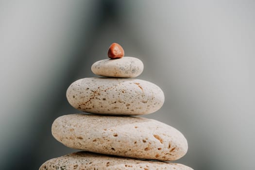 Pyramid stones on the seashore with warm sunset on the sea background. Happy holidays. Pebble beach, calm sea, travel destination. Concept of happy vacation on the sea, meditation, spa, calmness.