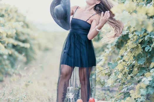 Woman at autumn winery. Portrait of happy woman holding glass of wine and enjoying in vineyard. Elegant young lady in hat toasting with wineglass smiling cheerfully enjoying her stay at vineyard