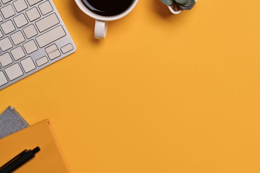 A coffee cup, keyboard and notebook on yellow background. Space for text advertising text message.