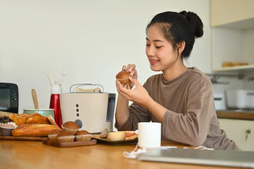 Young woman toasting bread with toaster for breakfast in the kitchen. People, food and domestic life concept.