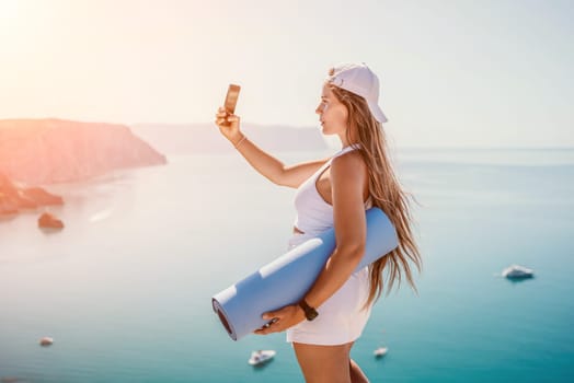 Young woman with black hair, fitness instructor in pink sports leggings and tops, doing pilates on yoga mat with magic pilates ring by the sea on the beach. Female fitness daily yoga concept